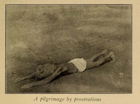 This devout man is traveling a great distance to a holy shrine by prostrating himself, rising, and then prostrating himself again.